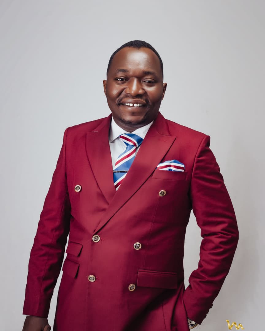 Pastor Ifeanyi Uwakwe in a burgundy double-breasted suit with a striped tie and matching pocket square.