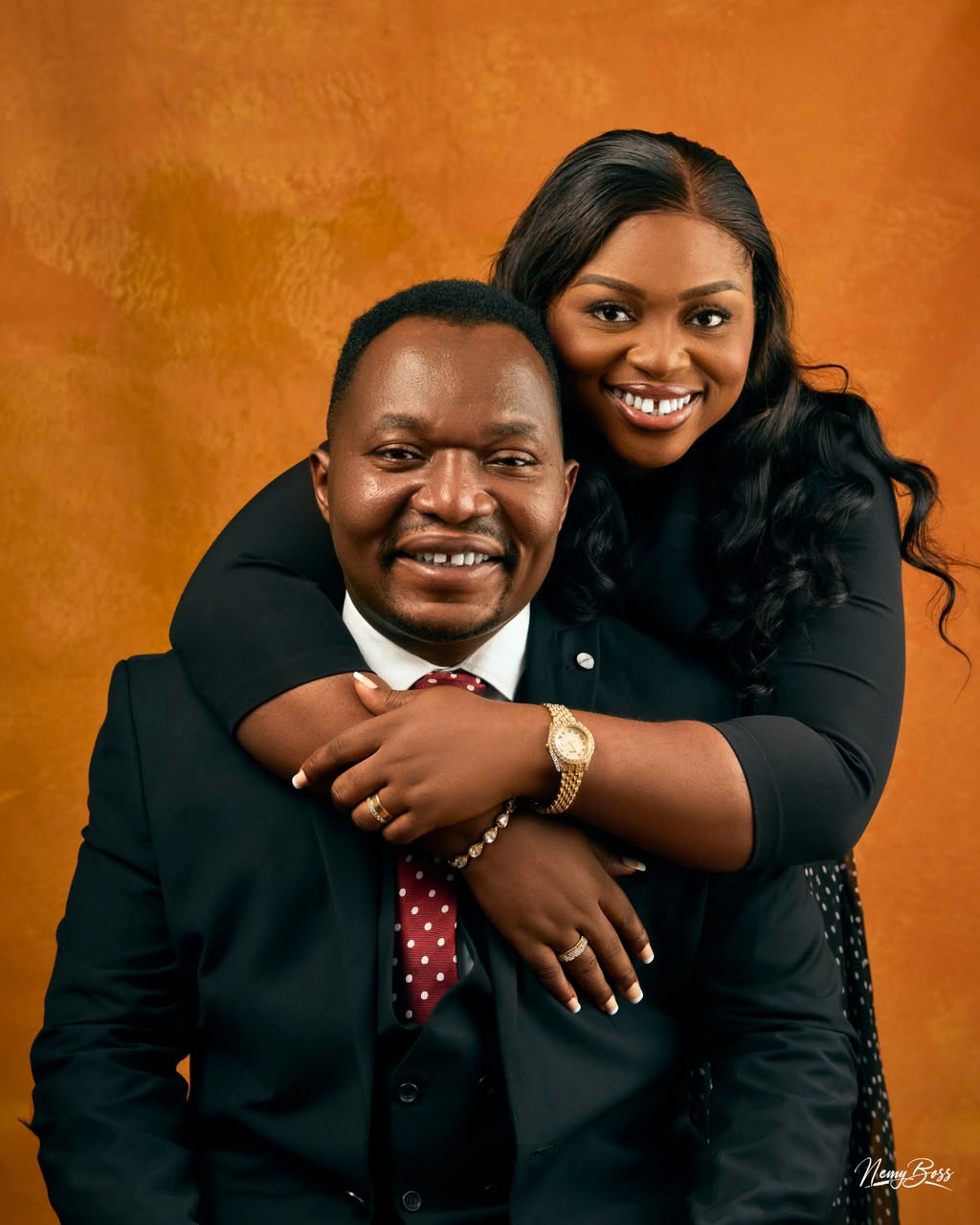 Pastor Ifeanyi Uwakwe with his wife, Pastor Kachi Uwakwe, against a warm ochre backdrop.